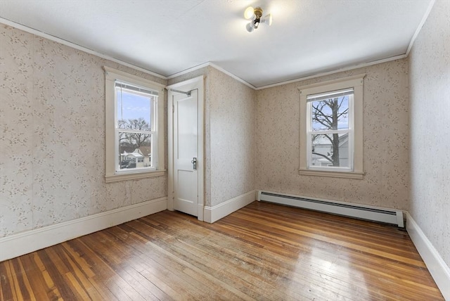 unfurnished room featuring baseboard heating, ornamental molding, wood finished floors, baseboards, and wallpapered walls