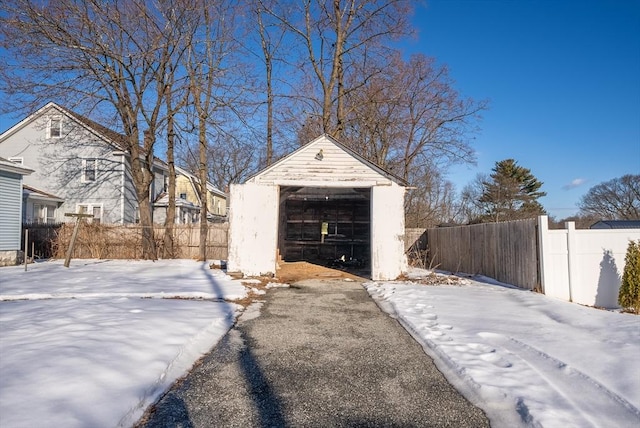 exterior space with a detached garage, fence, aphalt driveway, and an outbuilding