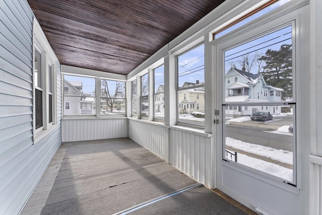 unfurnished sunroom with wooden ceiling and a residential view