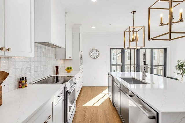 kitchen with white cabinets, light stone counters, decorative light fixtures, stainless steel appliances, and a sink