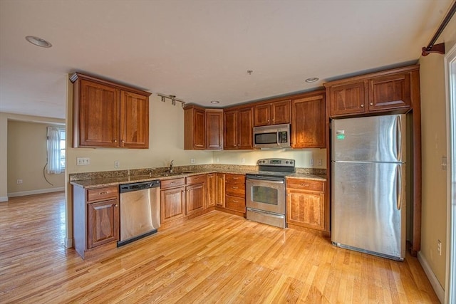 kitchen with sink, stainless steel appliances, and light hardwood / wood-style floors