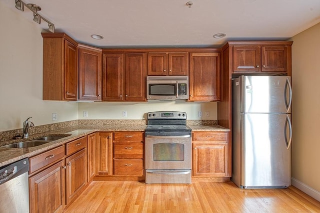 31 Freedom Cir Unit 31, Pembroke, MA 02359 - kitchen featuring stainless steel appliances, light wood-type flooring, light stone countertops, brown cabinets, and recessed lighting