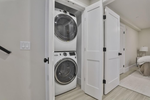 clothes washing area with stacked washing maching and dryer and light hardwood / wood-style flooring