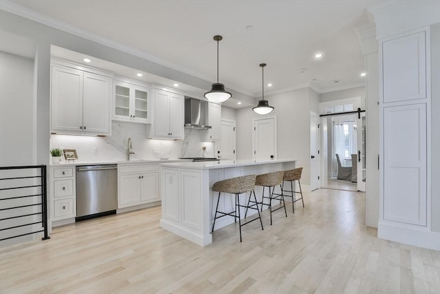 kitchen featuring a kitchen island, stainless steel appliances, wall chimney range hood, and white cabinets