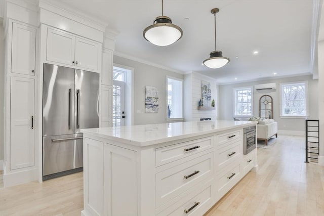 kitchen with white cabinetry, ornamental molding, light hardwood / wood-style floors, a wall mounted AC, and high end refrigerator