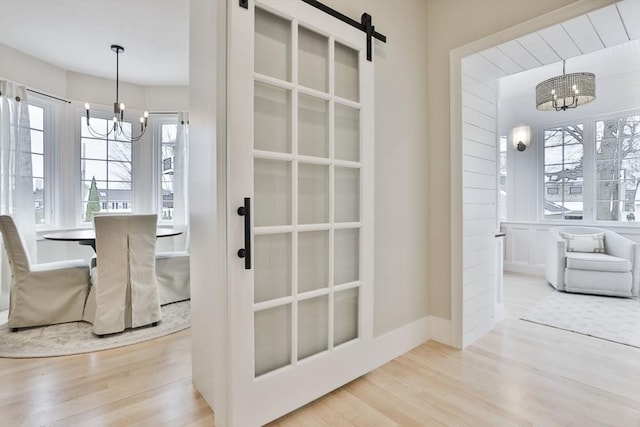 dining area featuring an inviting chandelier, light hardwood / wood-style floors, and a barn door