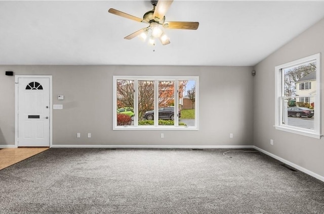 unfurnished living room with ceiling fan, carpet floors, and a wealth of natural light