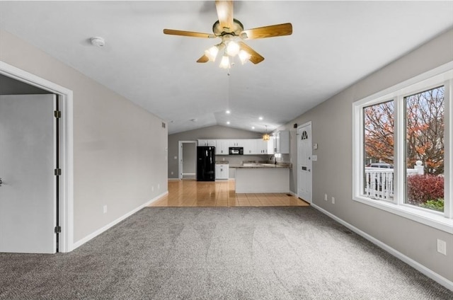 unfurnished living room with ceiling fan, light colored carpet, and vaulted ceiling