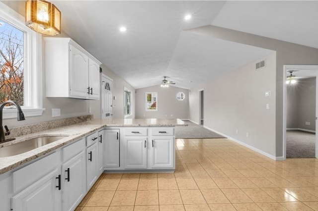 kitchen with ceiling fan, sink, kitchen peninsula, vaulted ceiling, and white cabinets