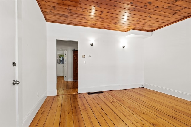 spare room featuring a barn door, wood ceiling, and wood-type flooring