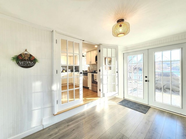 entryway featuring french doors, ornamental molding, and light hardwood / wood-style flooring