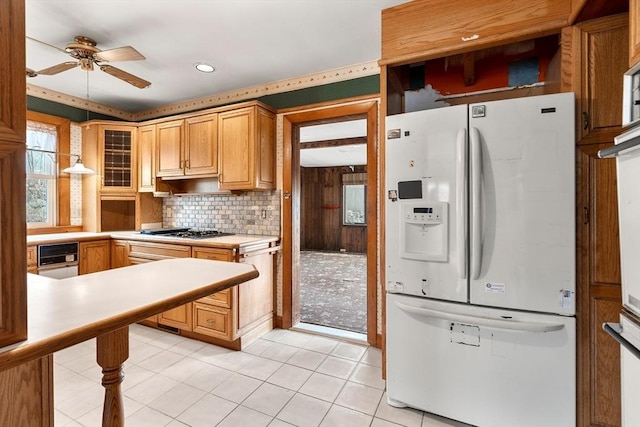 kitchen featuring backsplash, white fridge with ice dispenser, ceiling fan, light countertops, and stainless steel gas stovetop