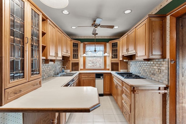 kitchen featuring a sink, gas stovetop, a peninsula, light countertops, and glass insert cabinets