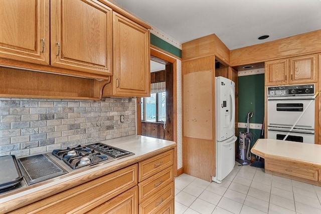 kitchen with white appliances, light tile patterned floors, light countertops, and backsplash