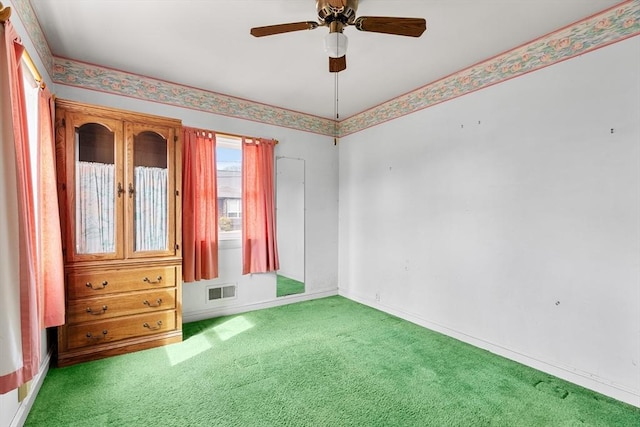 unfurnished bedroom with carpet flooring, baseboards, visible vents, and a ceiling fan