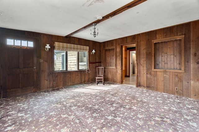 unfurnished living room featuring carpet flooring, wood walls, and beamed ceiling