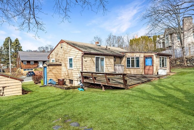 rear view of property featuring a wooden deck, a lawn, and a chimney