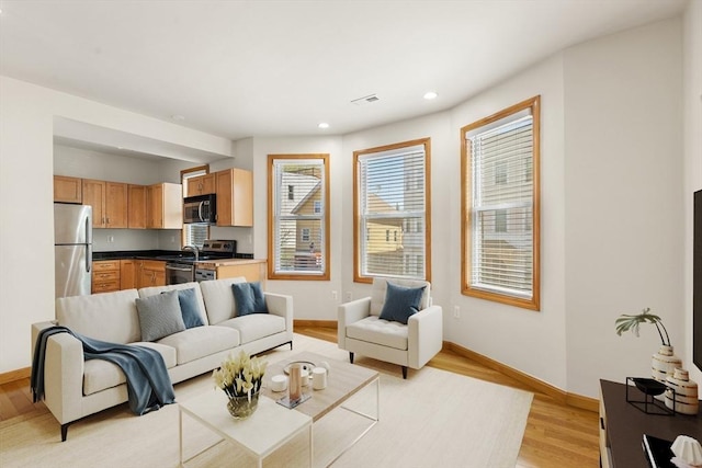 living area featuring light wood-type flooring, baseboards, and recessed lighting