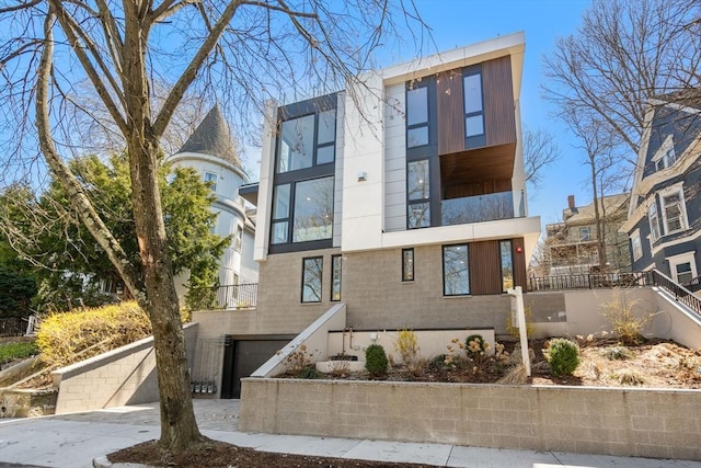 view of front of property with concrete driveway, a balcony, stucco siding, an attached garage, and fence
