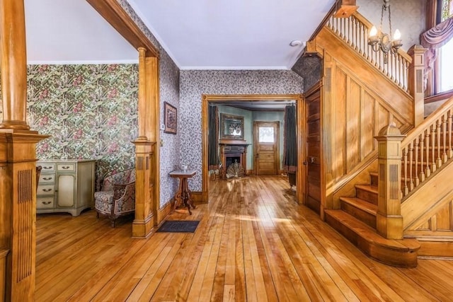 foyer featuring a chandelier, hardwood / wood-style flooring, a fireplace, stairs, and wallpapered walls