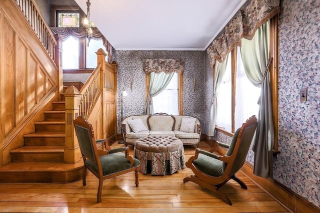 living area with hardwood / wood-style flooring, a healthy amount of sunlight, crown molding, and wallpapered walls