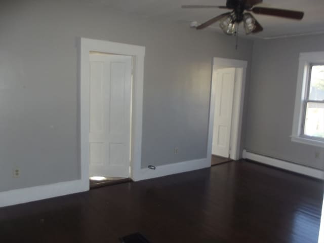 spare room with dark hardwood / wood-style floors, ceiling fan, and a baseboard heating unit