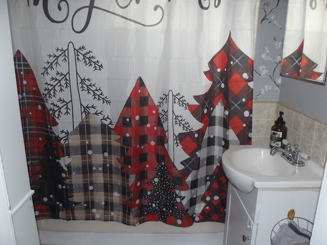 bathroom featuring vanity, backsplash, tile walls, and curtained shower