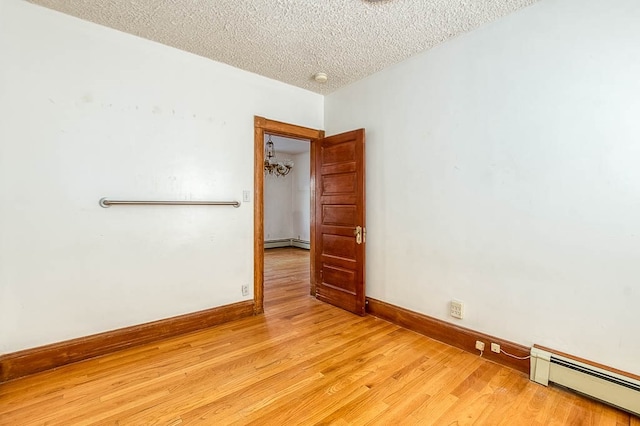 empty room with a baseboard radiator, a textured ceiling, and light wood-type flooring