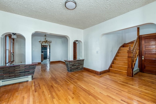 living room featuring a textured ceiling, light hardwood / wood-style flooring, a baseboard radiator, and a chandelier