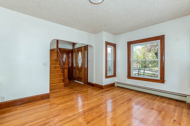 unfurnished room featuring a baseboard radiator, a textured ceiling, and light hardwood / wood-style floors