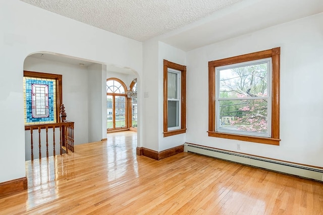 spare room featuring light wood-type flooring, a textured ceiling, and a baseboard radiator