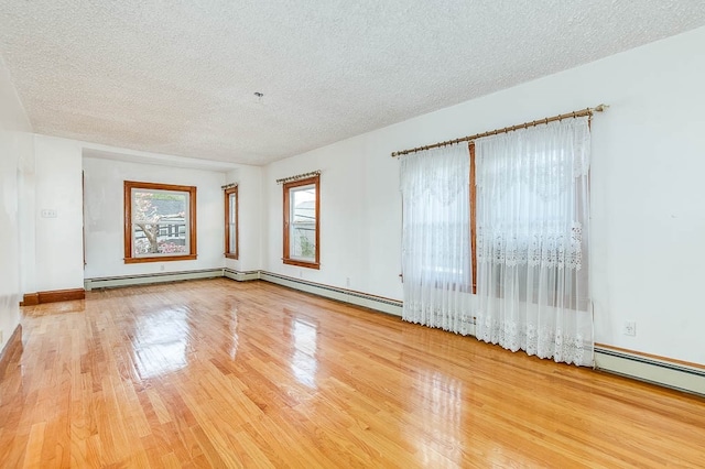 spare room featuring wood-type flooring, a textured ceiling, and a baseboard heating unit