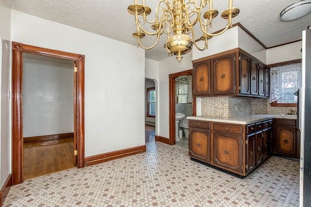 kitchen with a textured ceiling, dark brown cabinetry, hanging light fixtures, and a chandelier