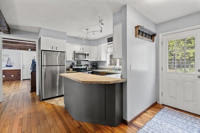 230 W St, Paxton, MA 01612 - kitchen with appliances with stainless steel finishes, a peninsula, light wood finished floors, white cabinetry, and wooden counters