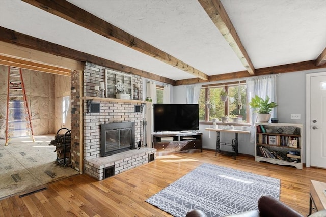 230 W St, Paxton, MA 01612 - living room featuring wood-type flooring, beam ceiling, and a brick fireplace