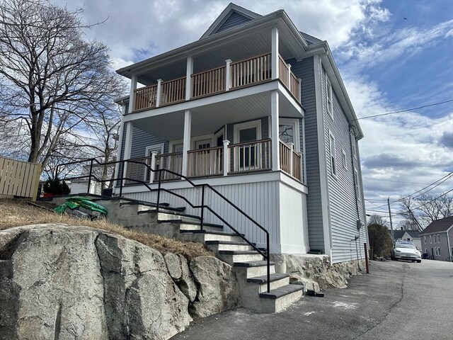 view of front of property featuring a porch, a balcony, and stairway