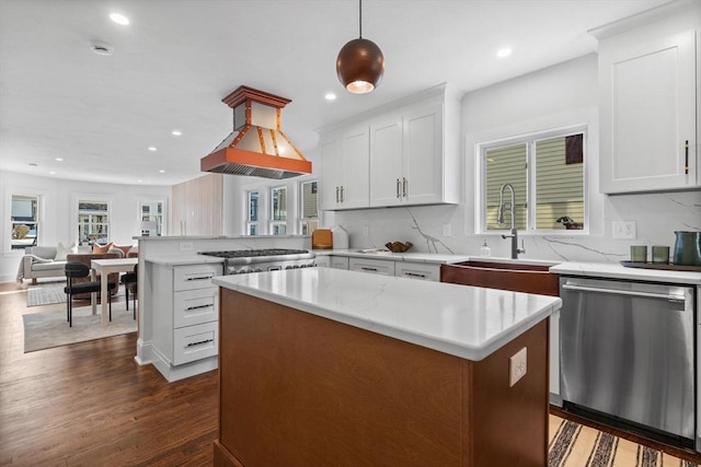 kitchen featuring appliances with stainless steel finishes, decorative light fixtures, sink, island exhaust hood, and a center island