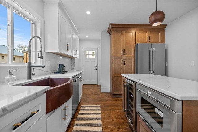 kitchen featuring sink, light stone counters, white cabinets, stainless steel appliances, and backsplash