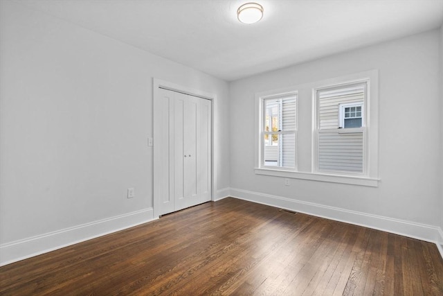 unfurnished bedroom featuring dark hardwood / wood-style floors and a closet