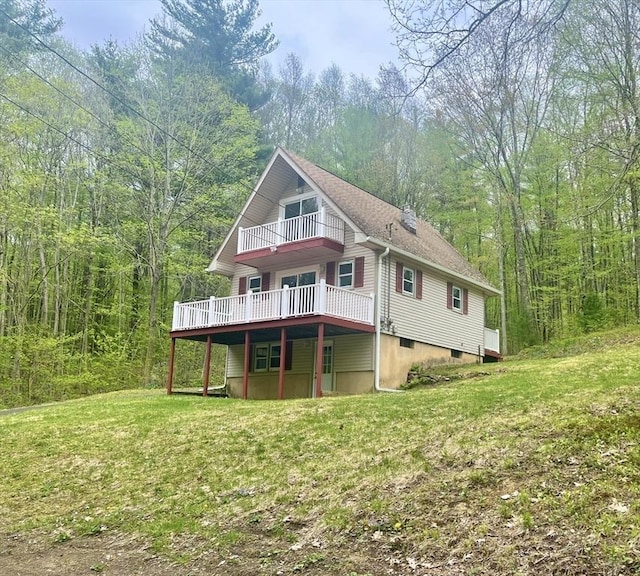 196 Munn Rd, Monson, MA 01057 - back of house with a balcony, a view of trees, a wooden deck, and a lawn