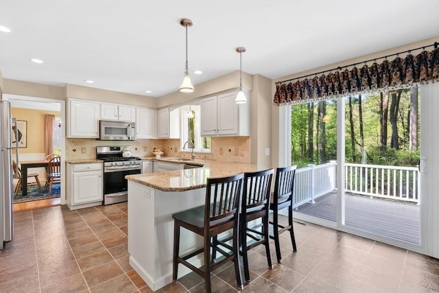 24 Heritage Cir E, Longmeadow, MA 01028 - kitchen featuring appliances with stainless steel finishes, a sink, a peninsula, light stone counters, and tasteful backsplash