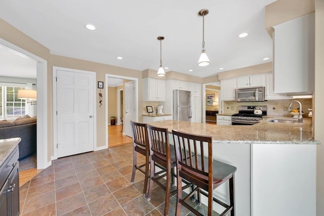 24 Heritage Cir E, Longmeadow, MA 01028 - kitchen featuring stainless steel appliances, a sink, a peninsula, baseboards, and light stone counters