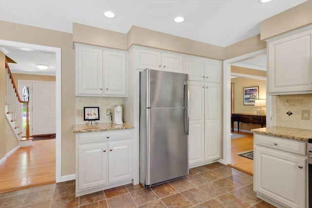 24 Heritage Cir E, Longmeadow, MA 01028 - kitchen featuring freestanding refrigerator, tasteful backsplash, white cabinets, light stone counters, and baseboards