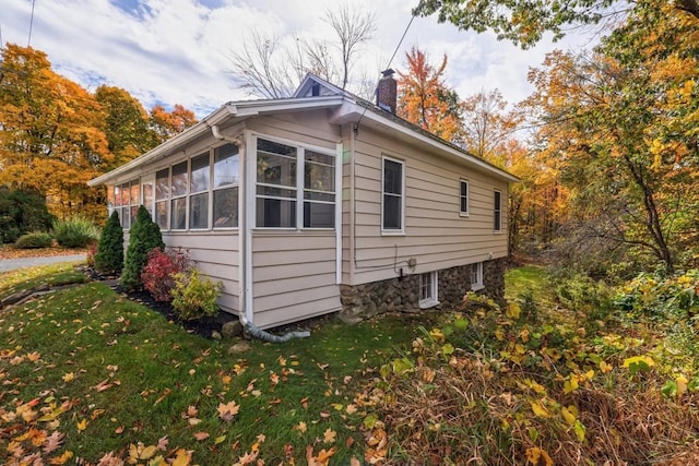 view of side of home with a sunroom and a lawn