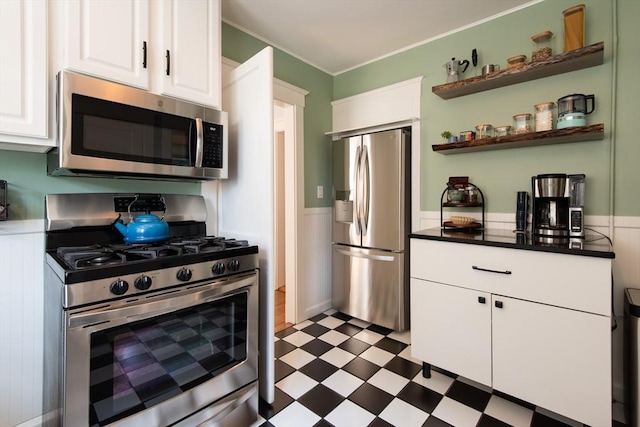 105 Fletcher St Unit 1, Boston, MA 02131 - kitchen with stainless steel appliances, dark floors, white cabinetry, a wainscoted wall, and crown molding