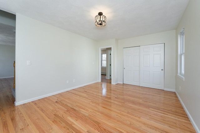 unfurnished bedroom with light wood-type flooring, baseboards, and a closet