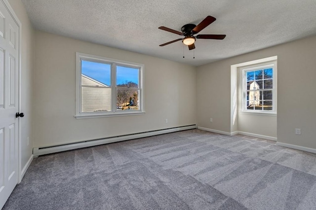 empty room with a baseboard heating unit, ceiling fan, baseboards, carpet flooring, and a textured ceiling