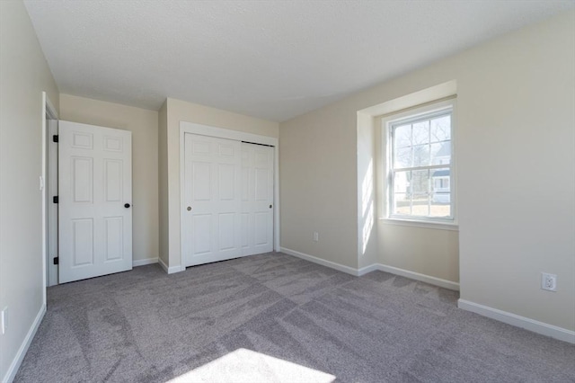 unfurnished bedroom with a closet, baseboards, a textured ceiling, and carpet flooring