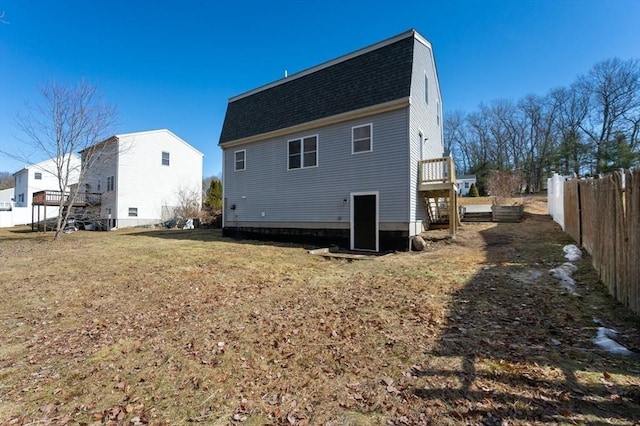 back of house with a gambrel roof, a shingled roof, and fence