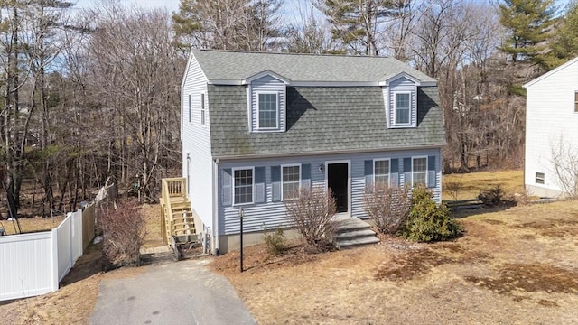 dutch colonial with fence, a gambrel roof, and a shingled roof